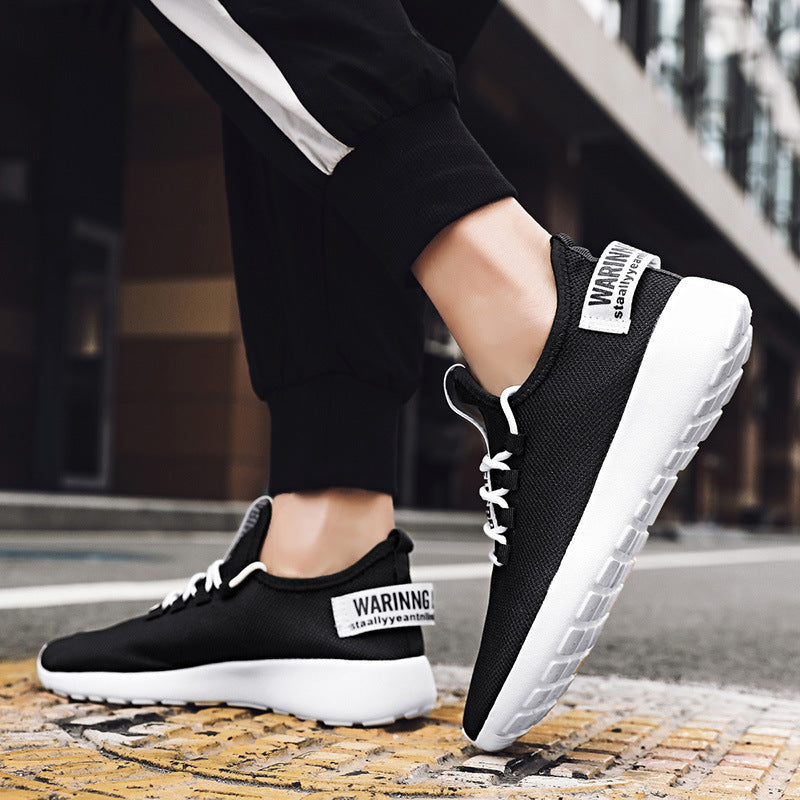 Black sneakers with white soles worn by a person on a street.