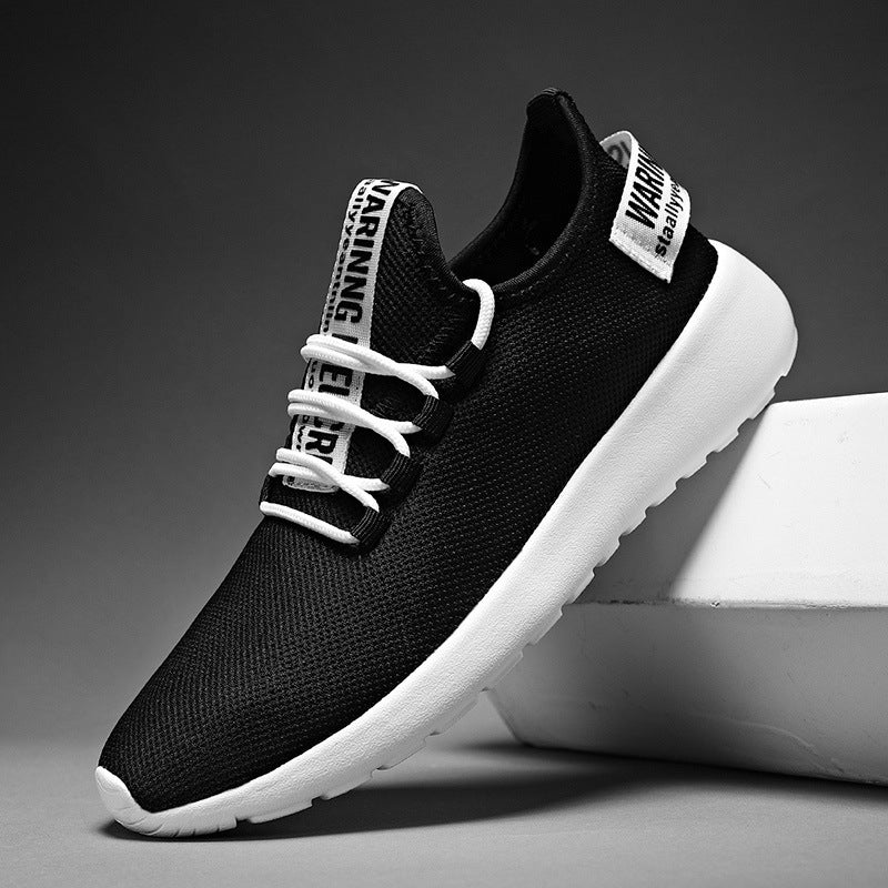 Black athletic shoes with white soles on a gray background