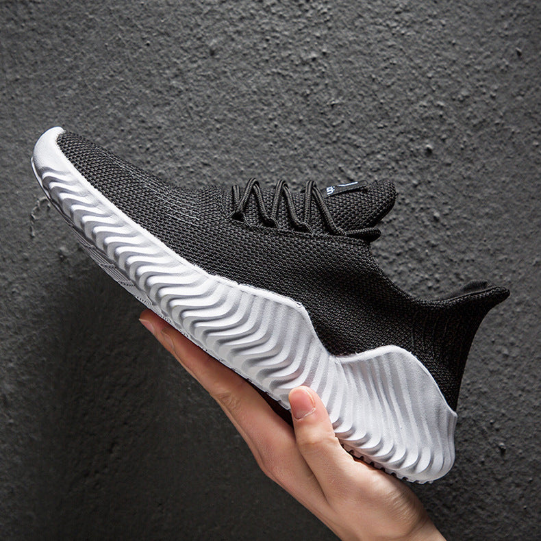 Black and white sneaker held in a hand against a dark background
