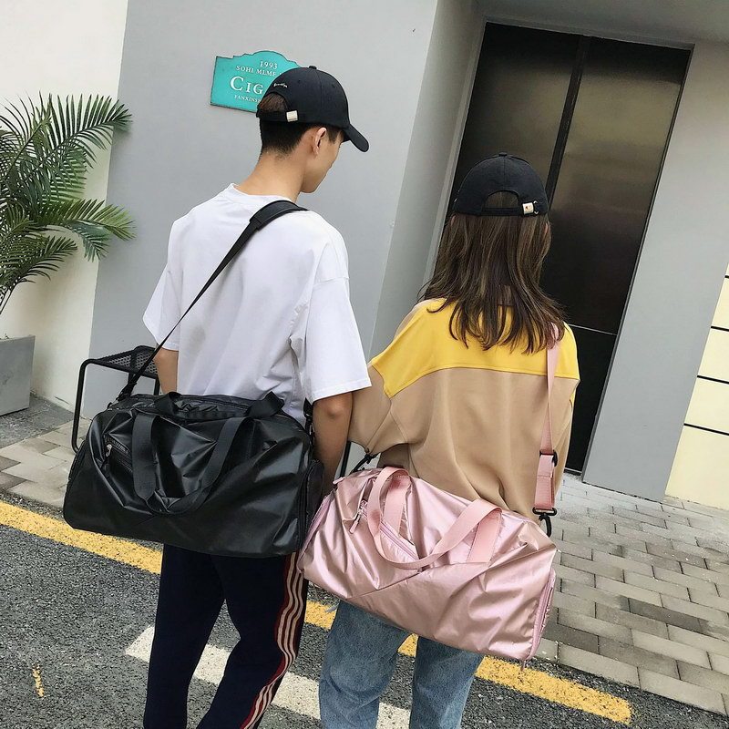 Two people walking outdoors with black and pink bags, wearing matching black caps.