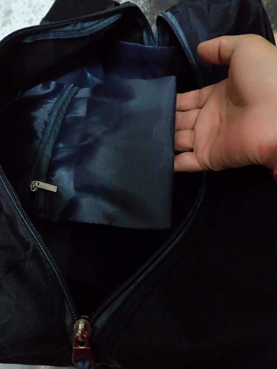 Hand opening a black jacket zipper with a blue lining.