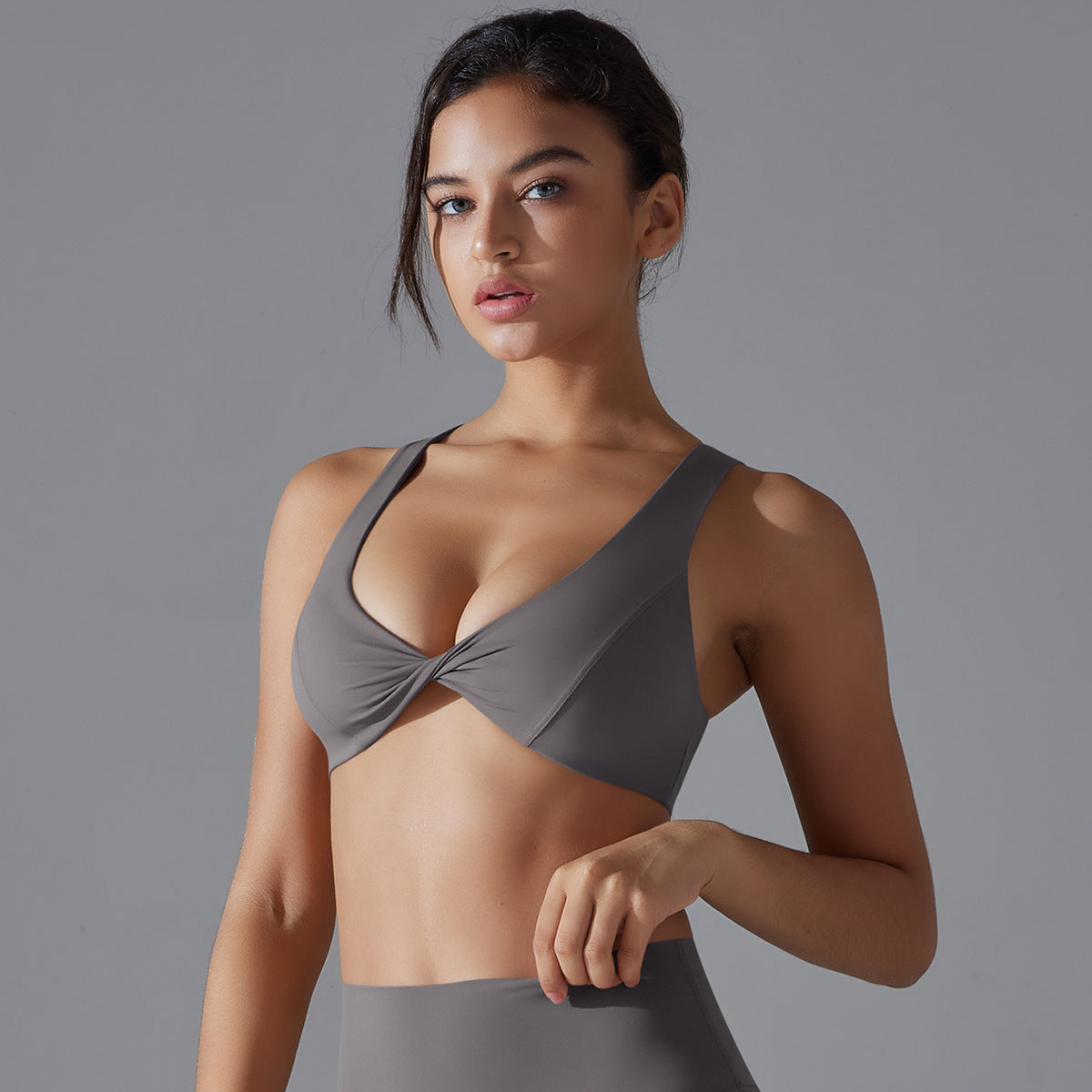 Woman wearing a gray sports bra and leggings on a gray background