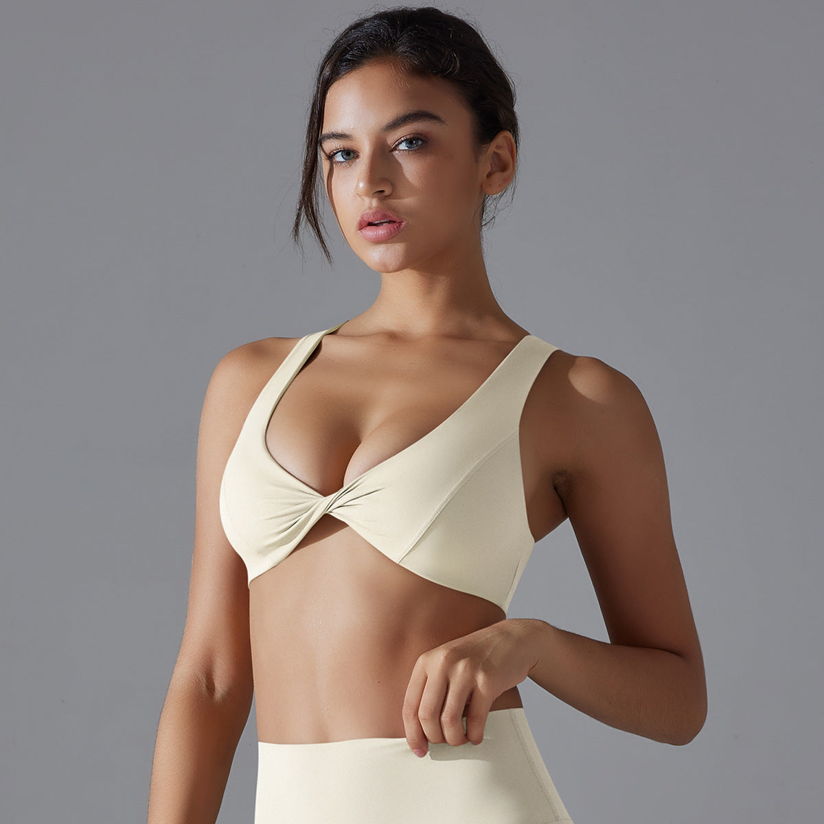 Woman wearing a beige bikini top against a gray background