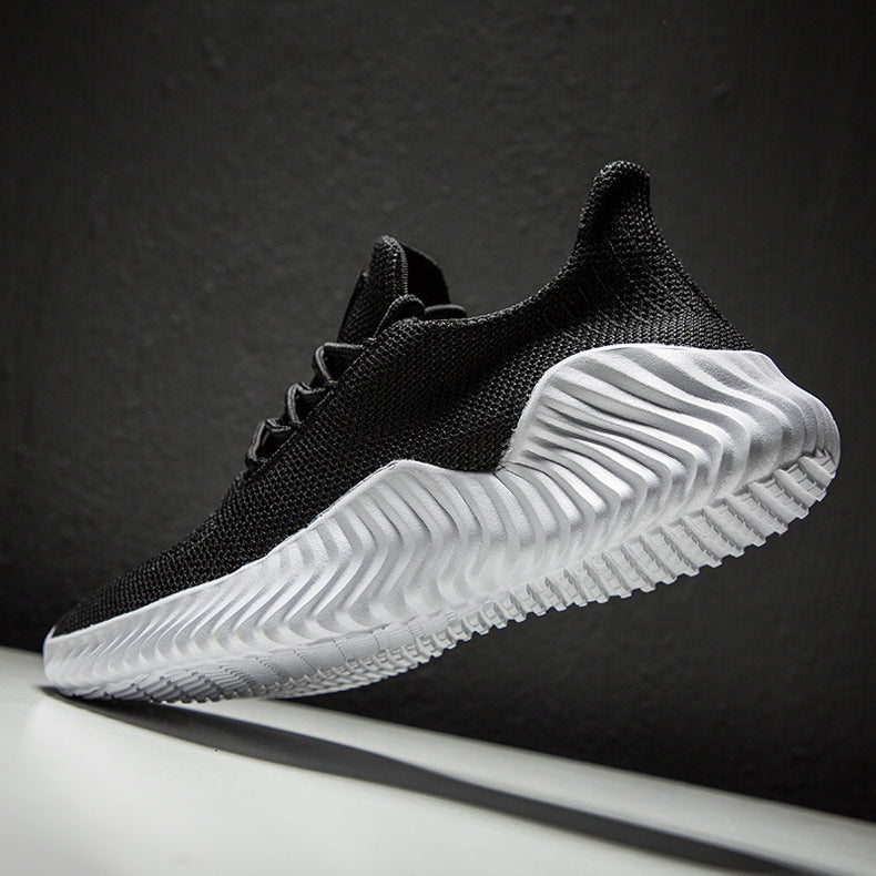 Black athletic shoe with white sole on a dark background