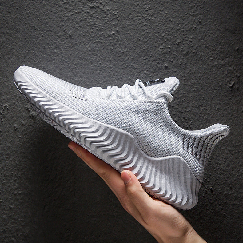 White athletic shoe held by a hand against a dark background