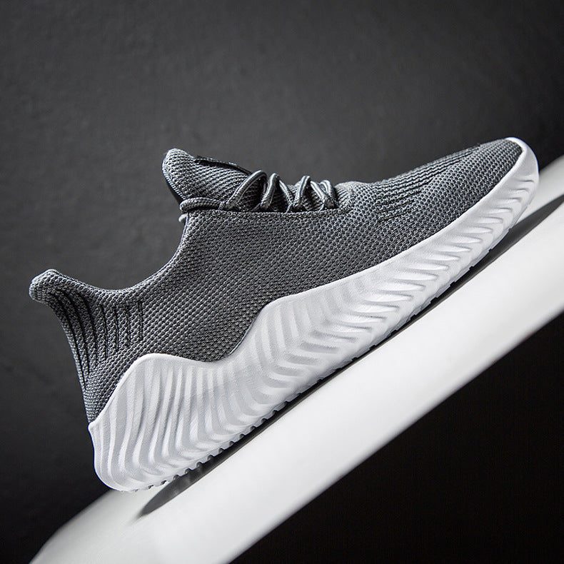 Gray athletic shoe with white sole on a dark background