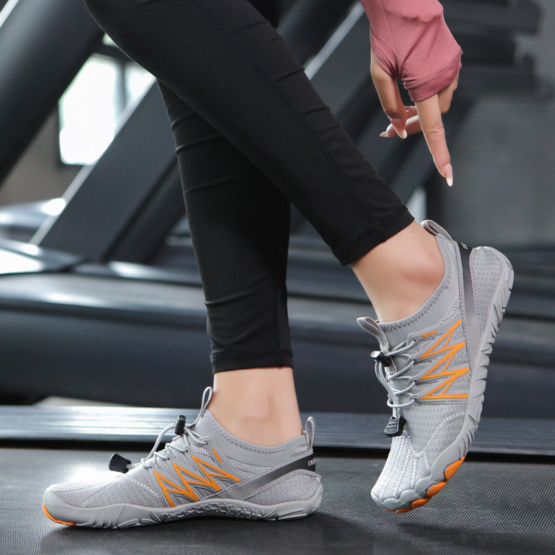 Person wearing gray athletic shoes with orange accents on a treadmill.