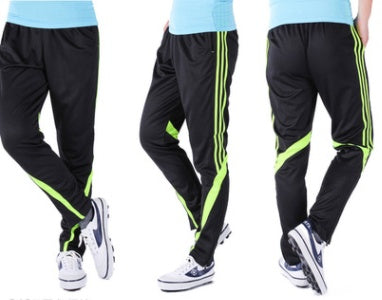 Black tracksuit pants with green stripes worn by a person on a white background