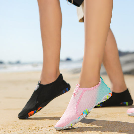 Person wearing black and pink water shoes on a beach.