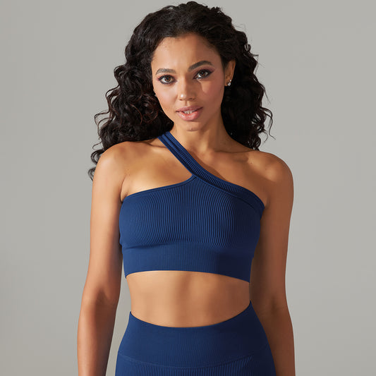 Woman wearing a blue one-shoulder top against a gray background