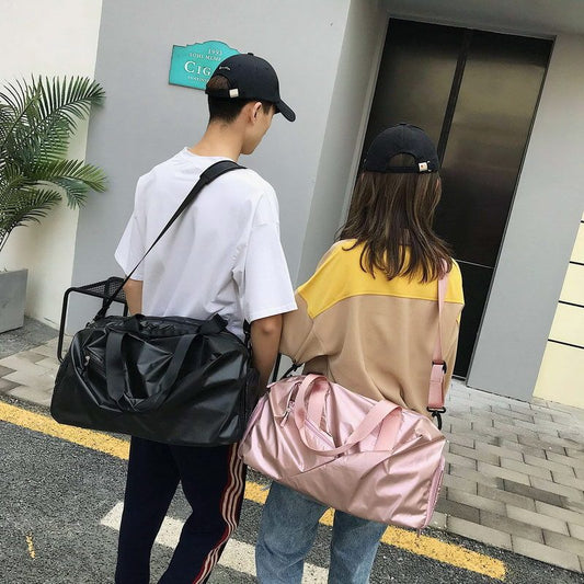 Two people walking outdoors with black and pink bags, wearing matching black caps.