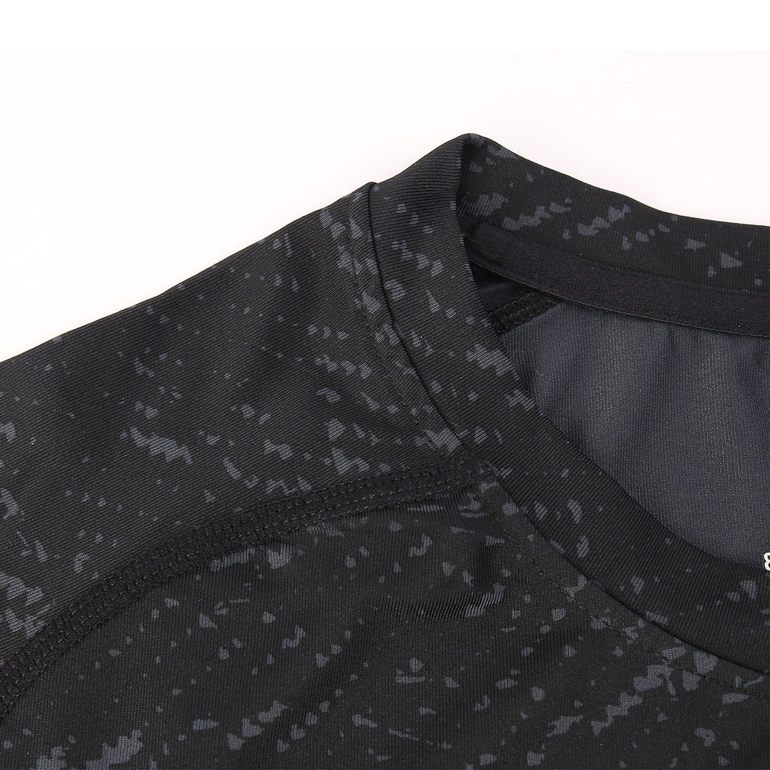 Close-up of a black athletic shirt with subtle pattern on a white background