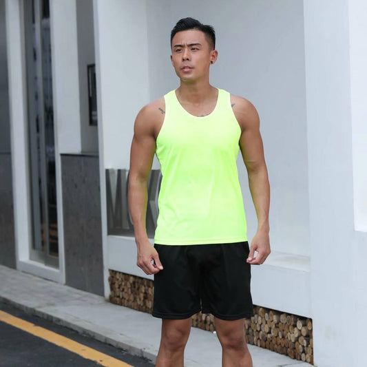 Man wearing a bright green tank top and black shorts standing on a street.
