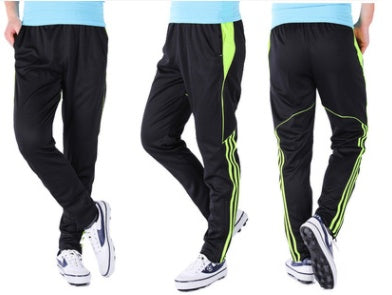 Black track pants with green stripes worn by a person on a white background