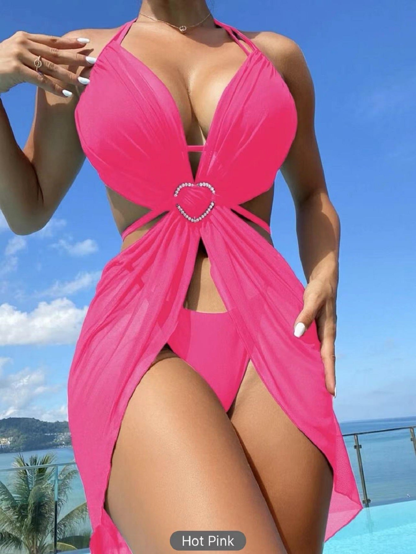 Hot pink swimsuit with a heart detail against a blue sky and ocean background