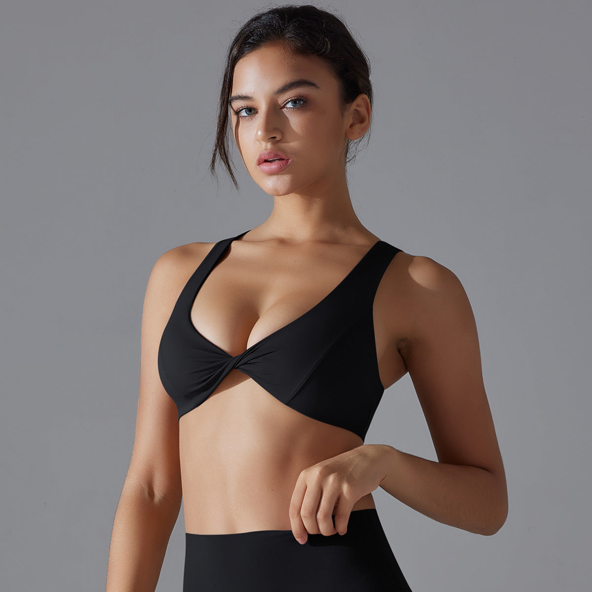 Woman wearing a black sports bra against a gray background
