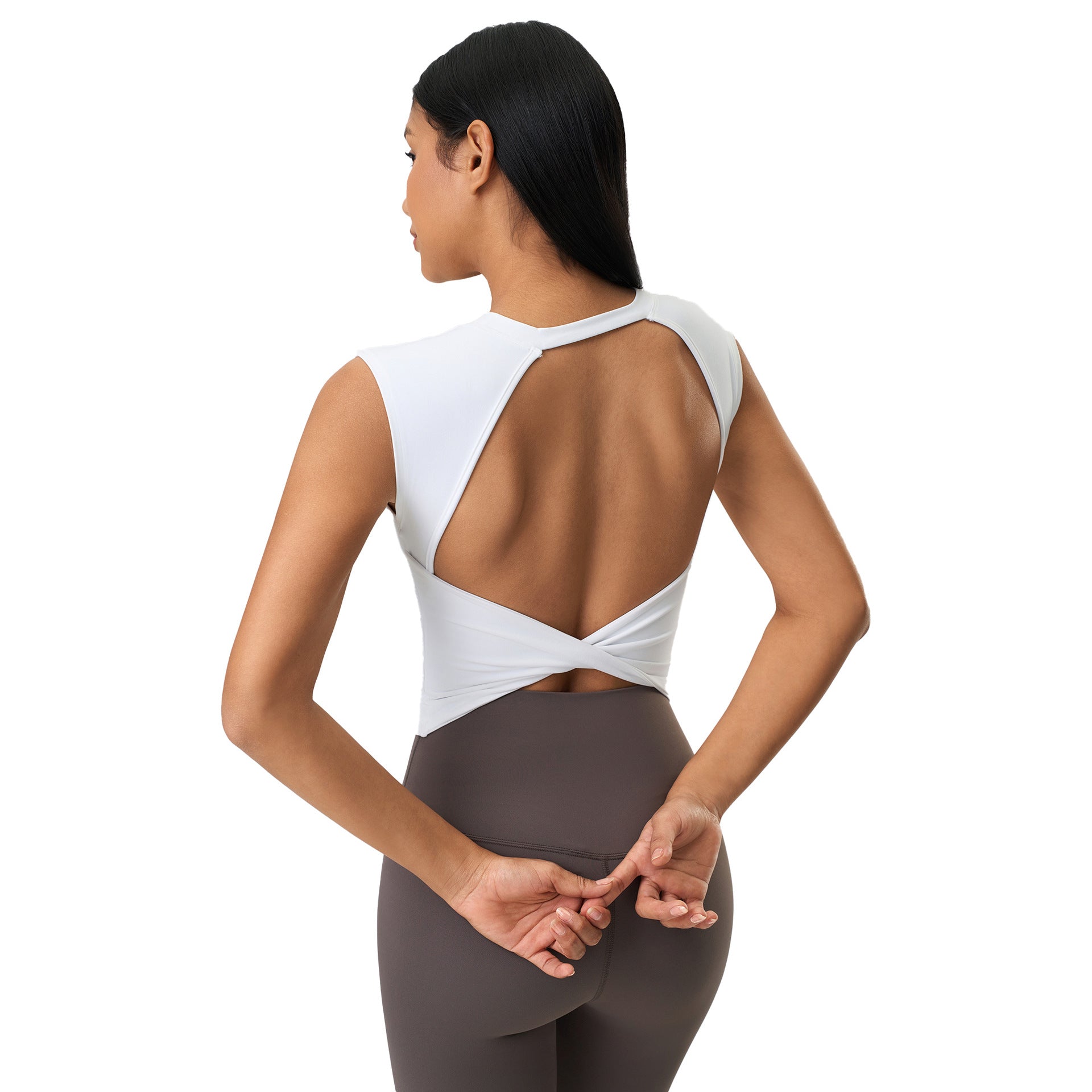 Woman wearing a white sleeveless top with cut-out design and brown leggings on a white background