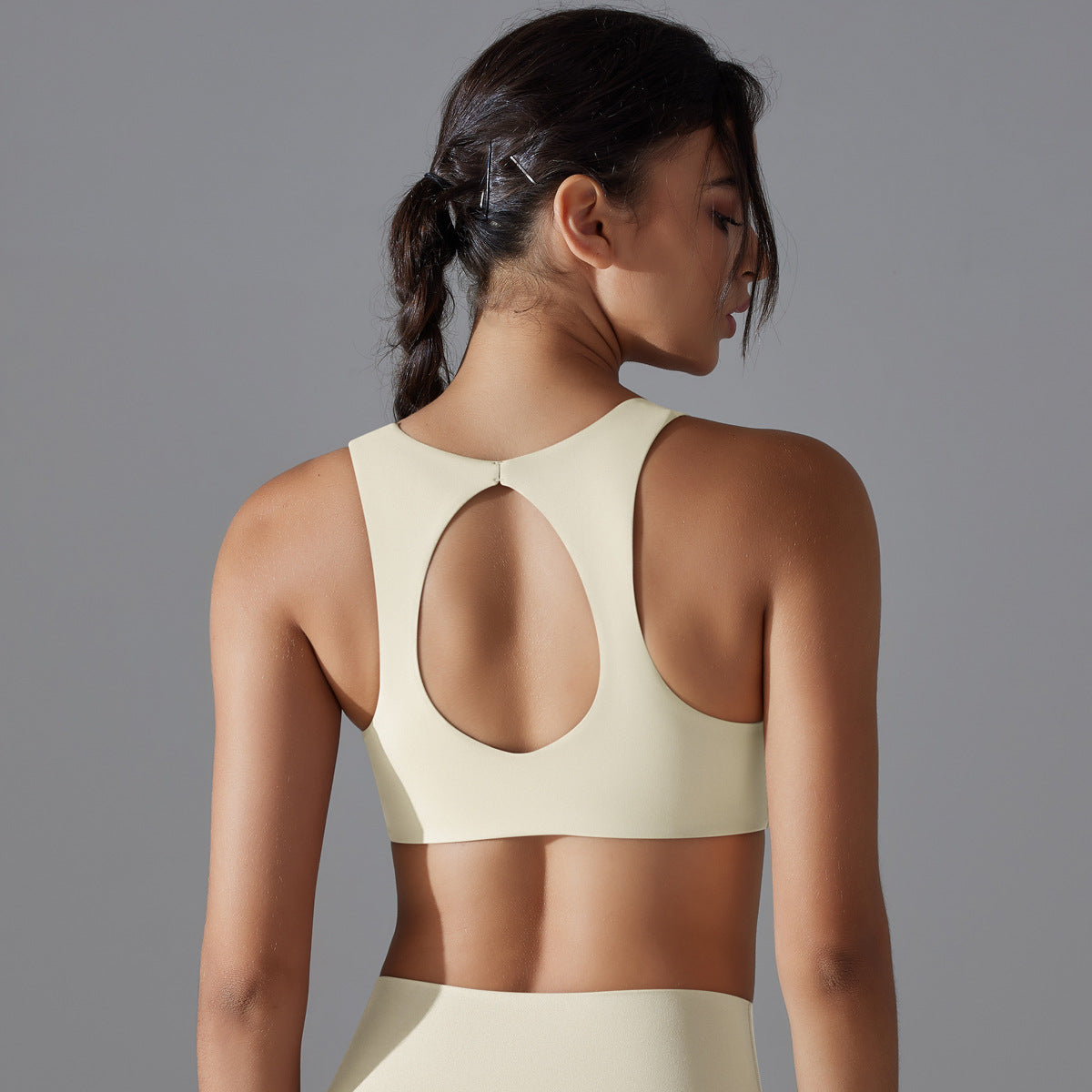 Woman wearing a beige sports bra and leggings against a gray background