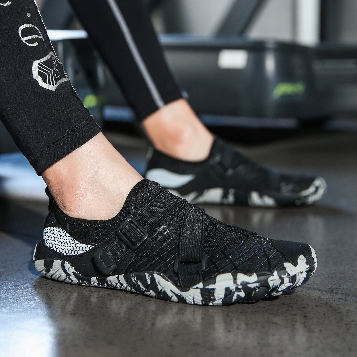 Black athletic shoe with white pattern on a dark surface