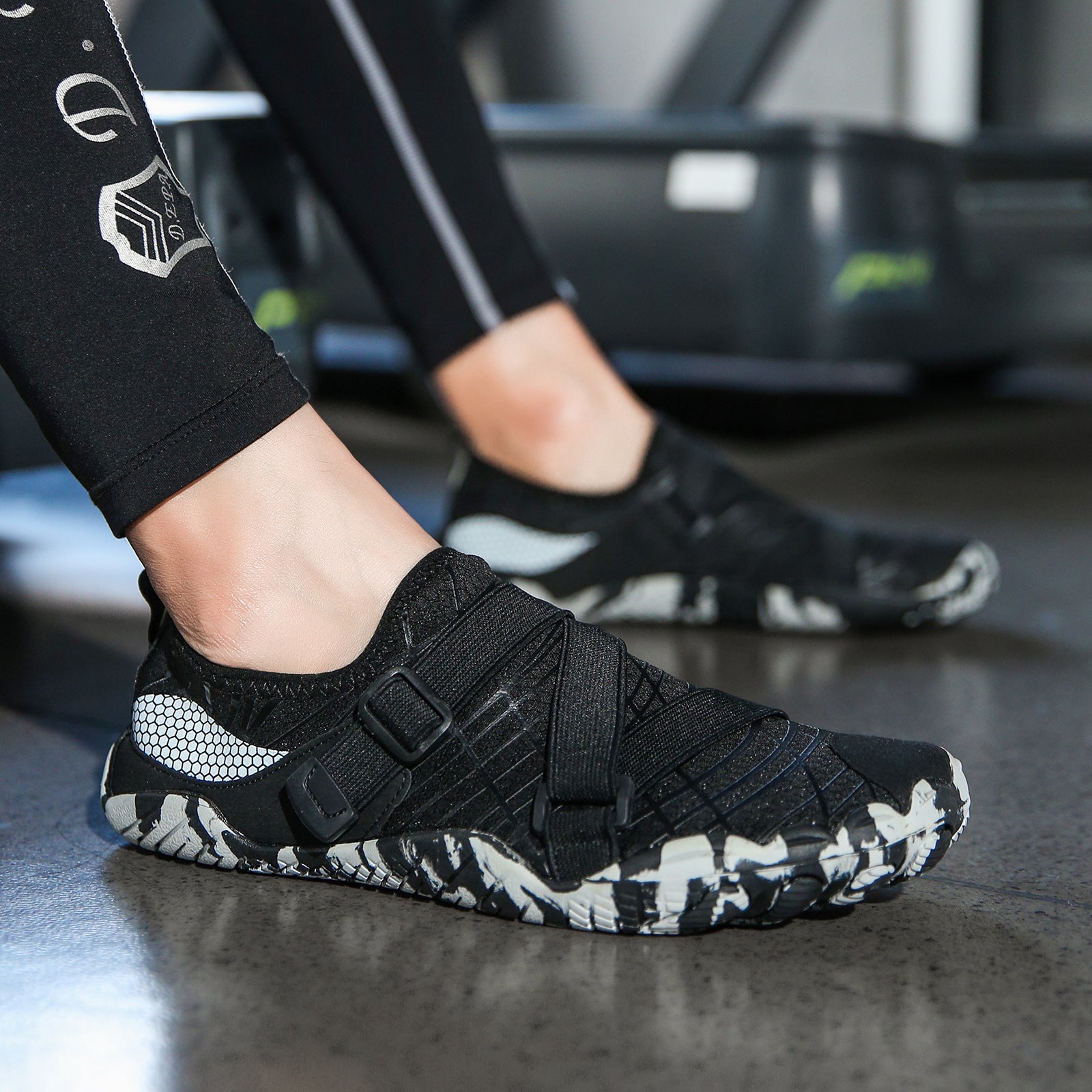 Black athletic shoe with white pattern on a dark surface